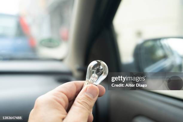 person´s hand holding  a light bulb inside a car. vehicle maintenance. - halogen light stock pictures, royalty-free photos & images