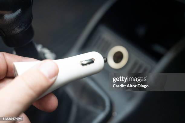 a person is going to plug usb adapter into the connection port of a car. - car plug adapter stock pictures, royalty-free photos & images