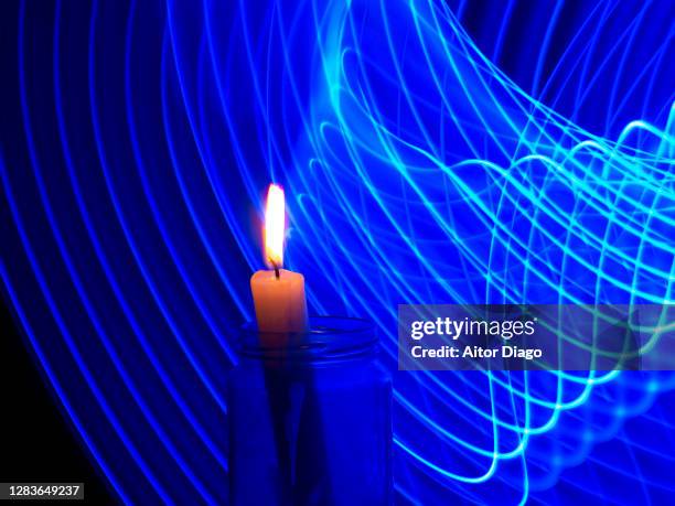 burning candle inside a transparent glass jar with a futuristic bluish background with moving curved lines. - computer burning stock pictures, royalty-free photos & images