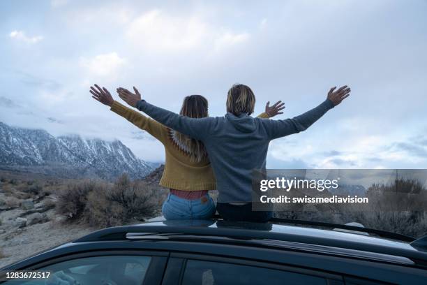 couple on car roof contemplate mountain landscape - car roof stock pictures, royalty-free photos & images