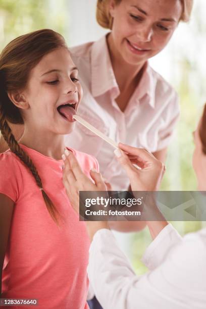 mother and girl during a throat exam in a consultarion room - tongue depressor stock pictures, royalty-free photos & images