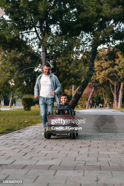 father and son playing in the park - man riding toy car stock pictures, royalty-free photos & images