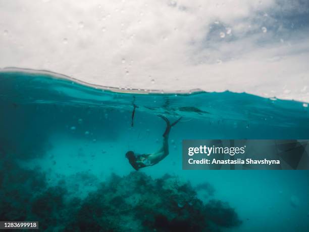 giovane donna che fai snorkeling ed esplora il mondo sottomarino vicino alla remota isola di zanzibar - half underwater foto e immagini stock