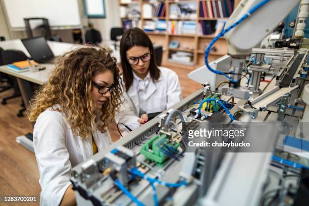 mujeres ingenieras arreglando una máquina - mechatronics fotografías e imágenes de stock