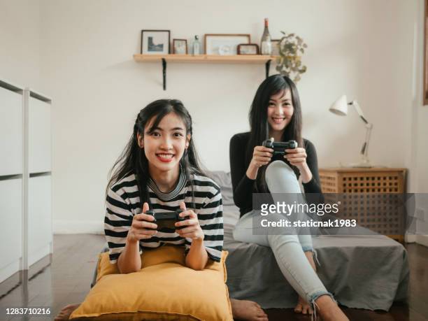 amis adolescents ayant du temps libre ensemble et jouant avec le jeu vidéo dans la chambre à coucher le week-end. - command sisters photos et images de collection
