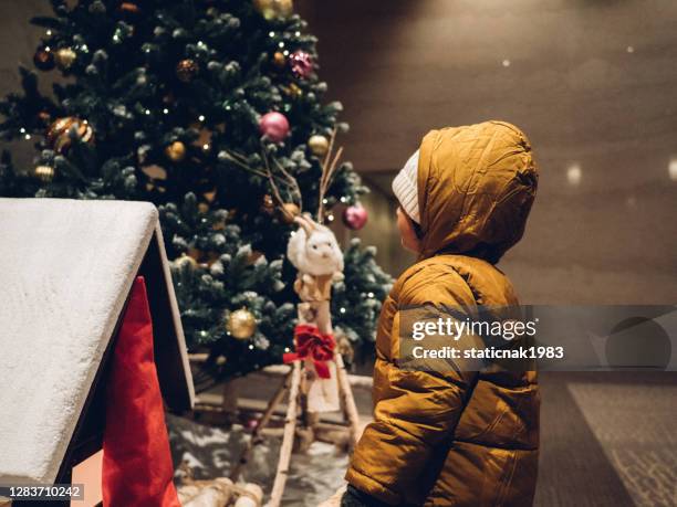 ein kleiner junge, der sich unter den weihnachtsdekorationen ansieht. - festival of remembrance 2019 stock-fotos und bilder