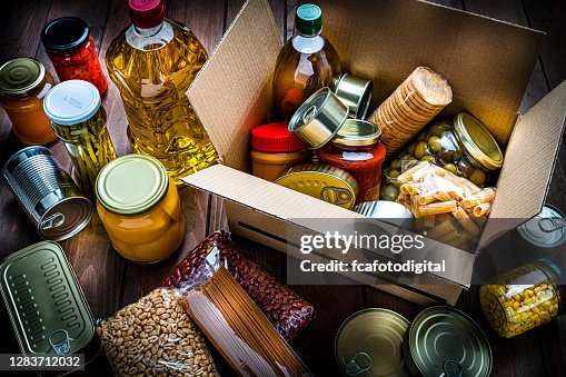 Cardboard box filled with non-perishable foods on wooden table. High angle view. Cardboard box filled with non-perishable foods on wooden table. High angle view.