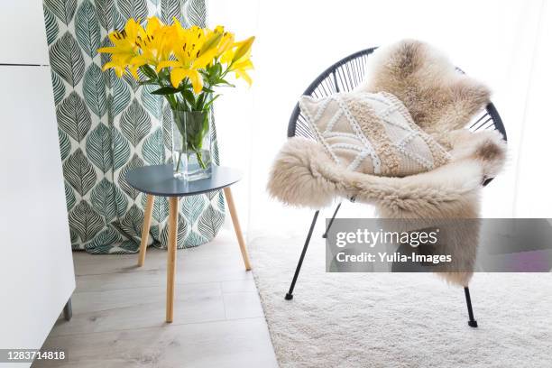 comfortable chair with sheepskin and cushion - metal flower arrangement stock pictures, royalty-free photos & images