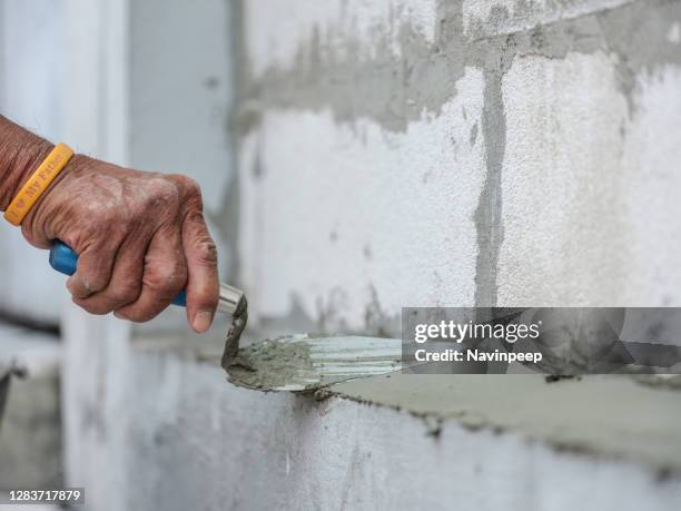 worker applying cement mortar on wall with trowel, masonry build from lightweight concrete block - truelle photos et images de collection