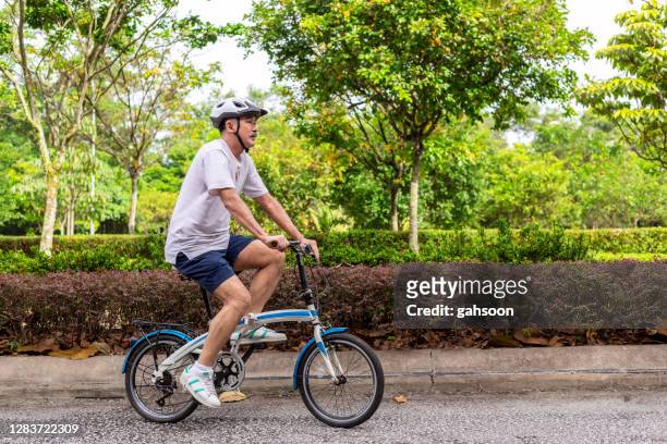 senior man gaan voor een fietstocht in het park - folding bike stockfoto's en -beelden