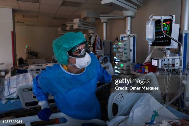Nurse wears a protective suit, mask, gloves and goggles as she checks the vital signs of a patient at the ICU of Krakow University Hospital on...