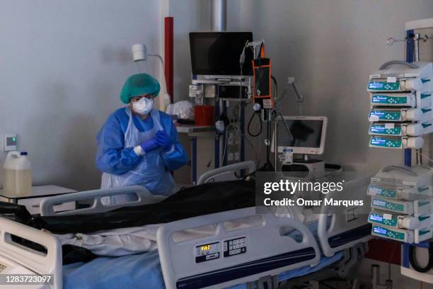 Nurse wears a protective suit, mask, gloves and goggles as she checks the vital signs of covers the body of a patient at the ICU of Krakow University...