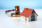 Real estate law and house auction concepts. A judge hammer and a house on a blue background.