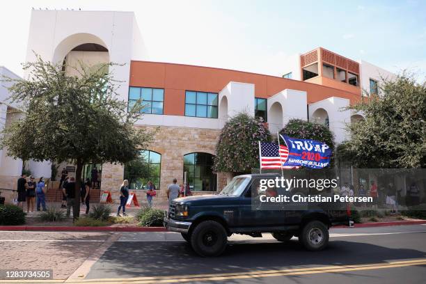 Truck displaying pro-Trump flags drives past voters as they stand in line at the Surprise Court House polling location on November 03, 2020 in...