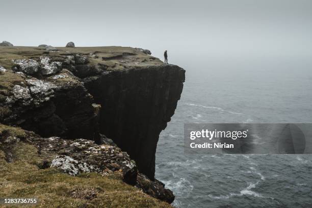 silhouette of a tourist standing on a cliff top - cliff stock pictures, royalty-free photos & images