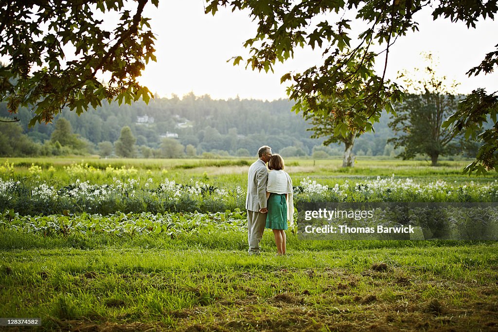Couple holding hands standing in field on farm