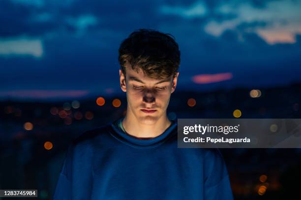 joven con vistas a la ciudad por la noche - shy fotografías e imágenes de stock