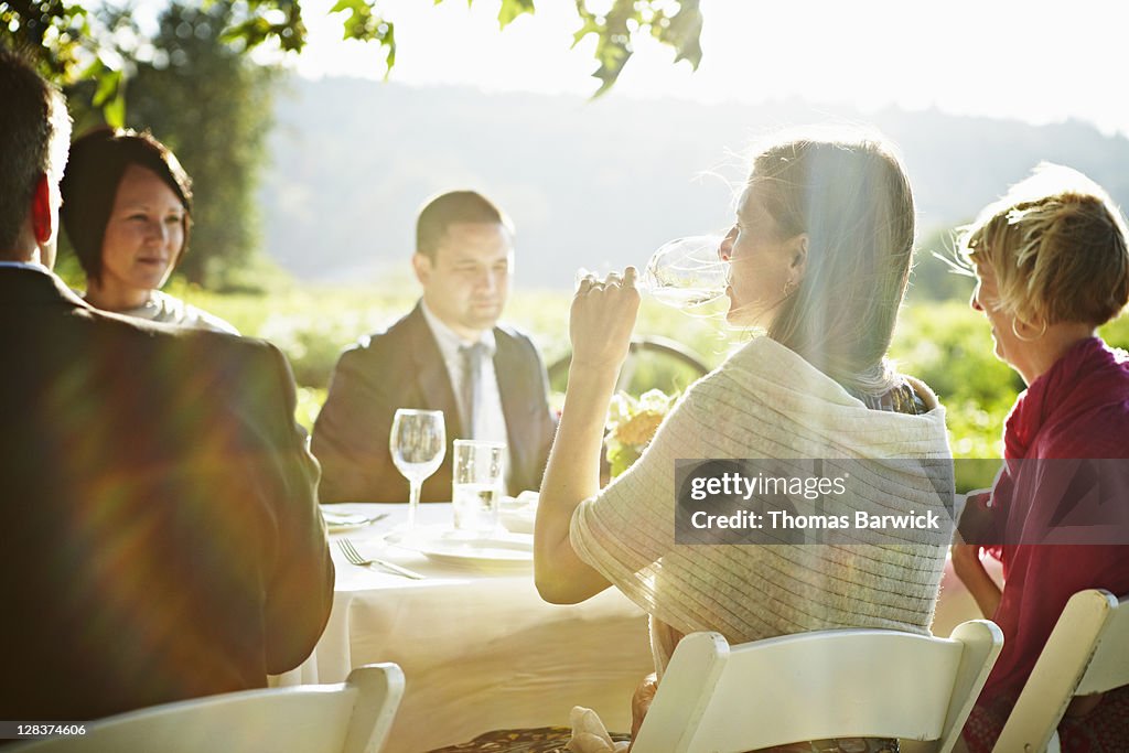 Woman sitting at outdoor table drinking wine