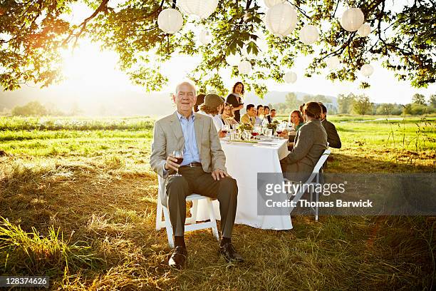 senior man sitting at head of table outside - prosperity stock pictures, royalty-free photos & images