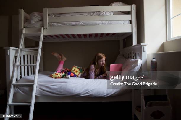 teenage girl studying on laptop computer in bedroom - 二段ベッド ストックフォトと画像