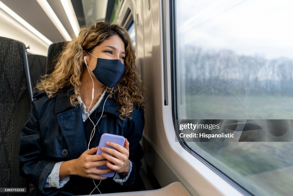 Mujer feliz viajando en tren con una máscara facial