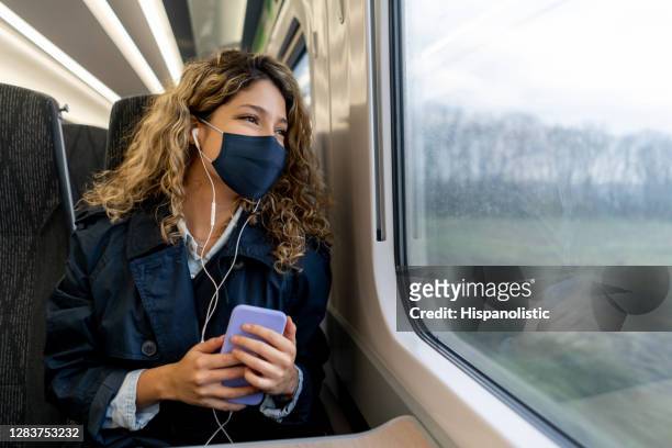 donna felice che viaggia in treno indossando una maschera facciale - pendolare foto e immagini stock
