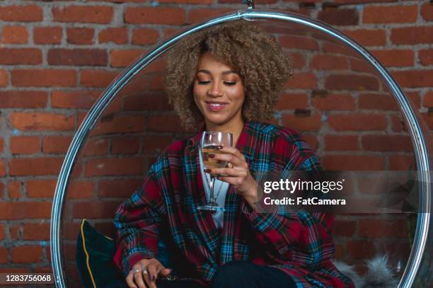 de jonge vrouw geniet van een glas wijn - egg chair stockfoto's en -beelden