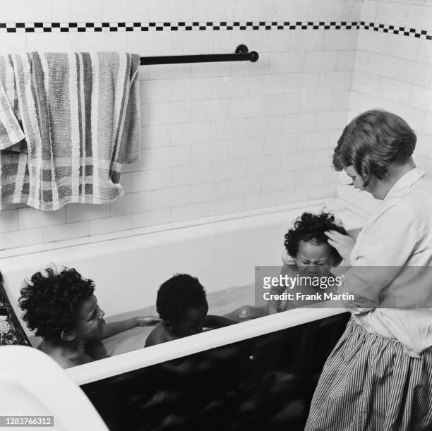 The mixed race Long family of Olyffe Avenue in Welling, Kent, July 1960. Twelve-year-old Joan helps bath her adopted twin sisters Mitch and Frankie,...