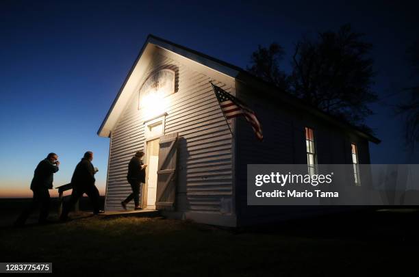 Voters enter a polling place at dusk to cast their ballots at Sherman Township Hall, a former one room schoolhouse, on November 3, 2020 in Zearing,...