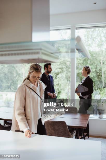 real estate agent talking to man while woman examining furniture in new house - real estate appraisal stock pictures, royalty-free photos & images