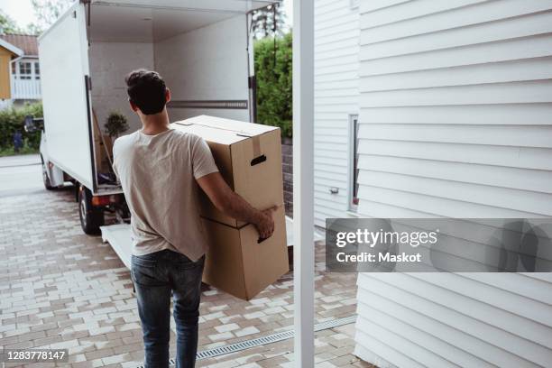 rear view of man carrying cardboard boxes towards van - man hauling stock pictures, royalty-free photos & images