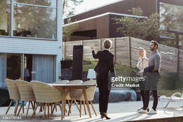 rear view of female agent showing new property to couple outdoors - real estate agent stock pictures, royalty-free photos & images