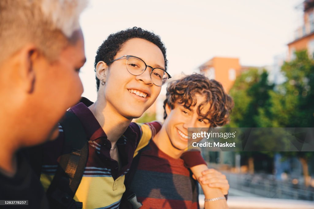 Portrait of smiling man with teenage friends standing in city