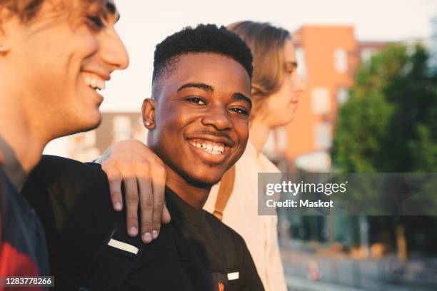 portrait of smiling young man with friends standing in city - sunset freinds city fotografías e imágenes de stock