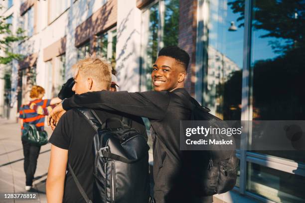 portrait of smiling young male with friend walking in city - boy looking over shoulder stock pictures, royalty-free photos & images