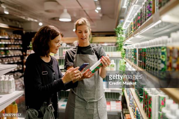 saleswoman assisting female customer in supermarket - mobile services stock pictures, royalty-free photos & images