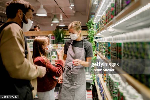 girl talking to saleswoman by father in supermarket during covid-19 - customer experience stock pictures, royalty-free photos & images