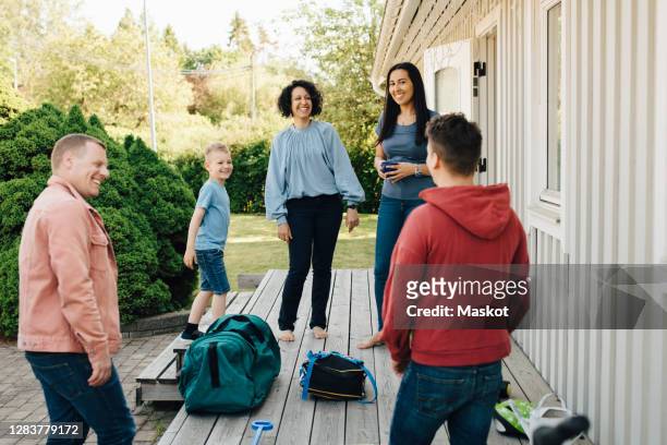 smiling mothers and son looking at gay couple standing by patio during weekend - child custody stock pictures, royalty-free photos & images