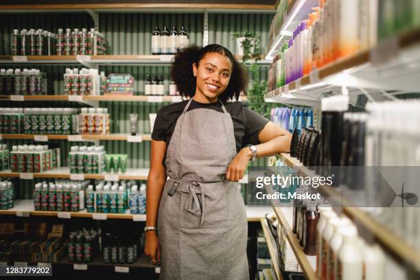 portrait of smiling saleswoman standing in supermarket - small business owner working stock-fotos und bilder