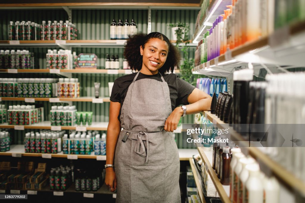 Portrait of smiling saleswoman standing in supermarket