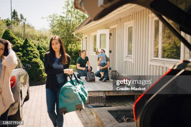 father embracing son while lesbian couple walking against house during sunny day - custody stock pictures, royalty-free photos & images