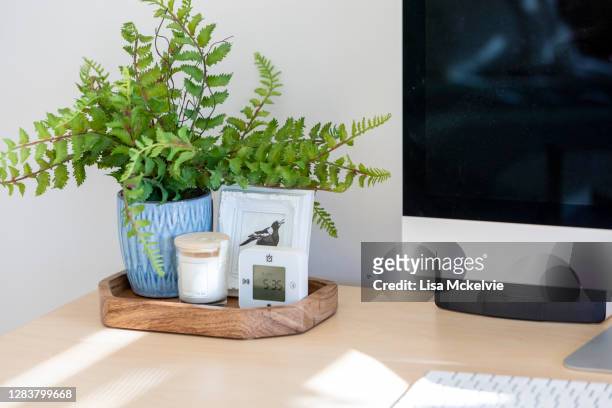 home office desk decor with a fern, picture frame, clock ad candle. - minimalist bedroom desk stock pictures, royalty-free photos & images