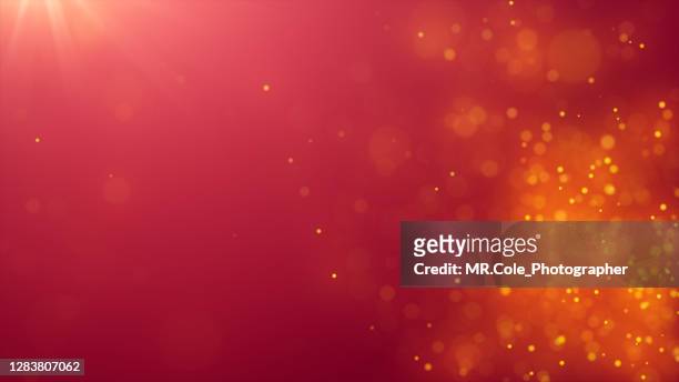 abstract background of de-focused gold colored particles on red background with lens flare - glamour stock pictures, royalty-free photos & images