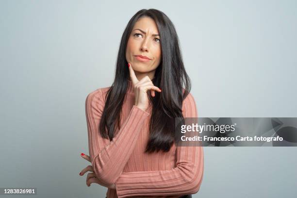 young lady making a thoughtful face - thoughtful woman stock pictures, royalty-free photos & images