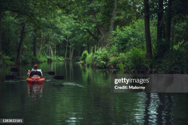 two women in kayak reading a map and floating through the forest. germany, brandenburg, spreewald, luebbenau - spreewald stock-fotos und bilder