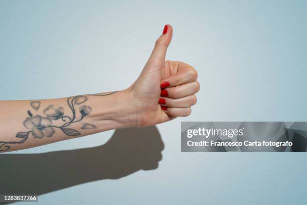 woman's hand making thumbs up sign - tattoo stock pictures, royalty-free photos & images