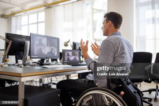 businessman with disability having a video call at his desk - differing abilities female business fotografías e imágenes de stock