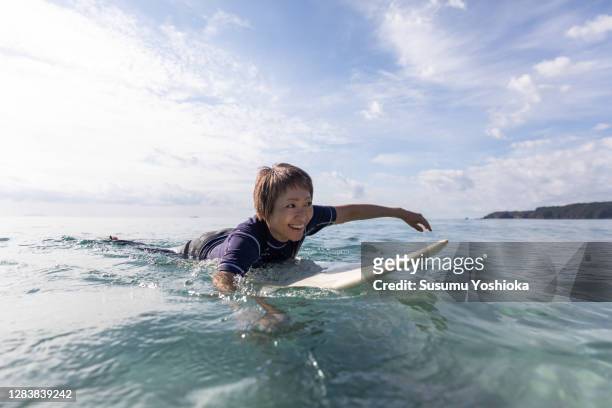 a woman surfing in the ocean - asian surfer stockfoto's en -beelden