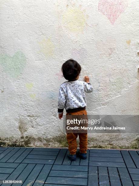 toddler drawing on wall with chalk - colombiaanse etniciteit stockfoto's en -beelden