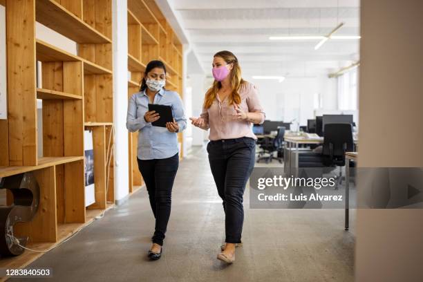 business partners walking in office and discussing work - corporate business covid stock pictures, royalty-free photos & images